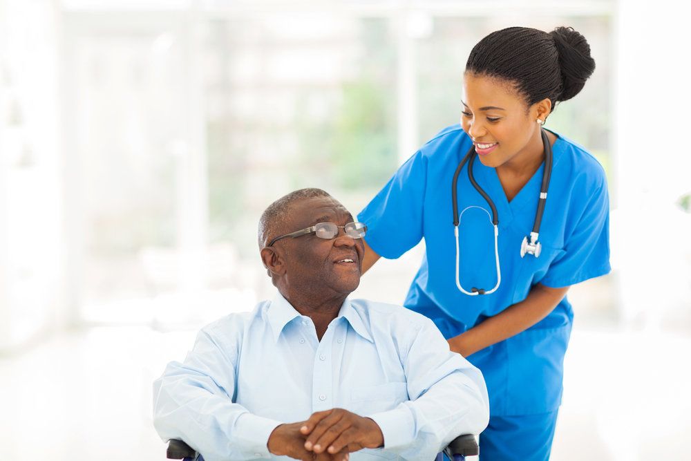 Nurse in scrubs helping patient in wheelchair